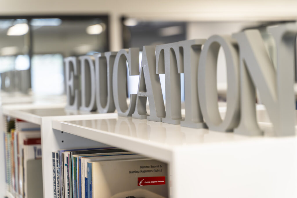 Artikkelikuvassa puisista kirjaimista muodostuva sana education kirjaston hyllyn päälle sijoitettuna.